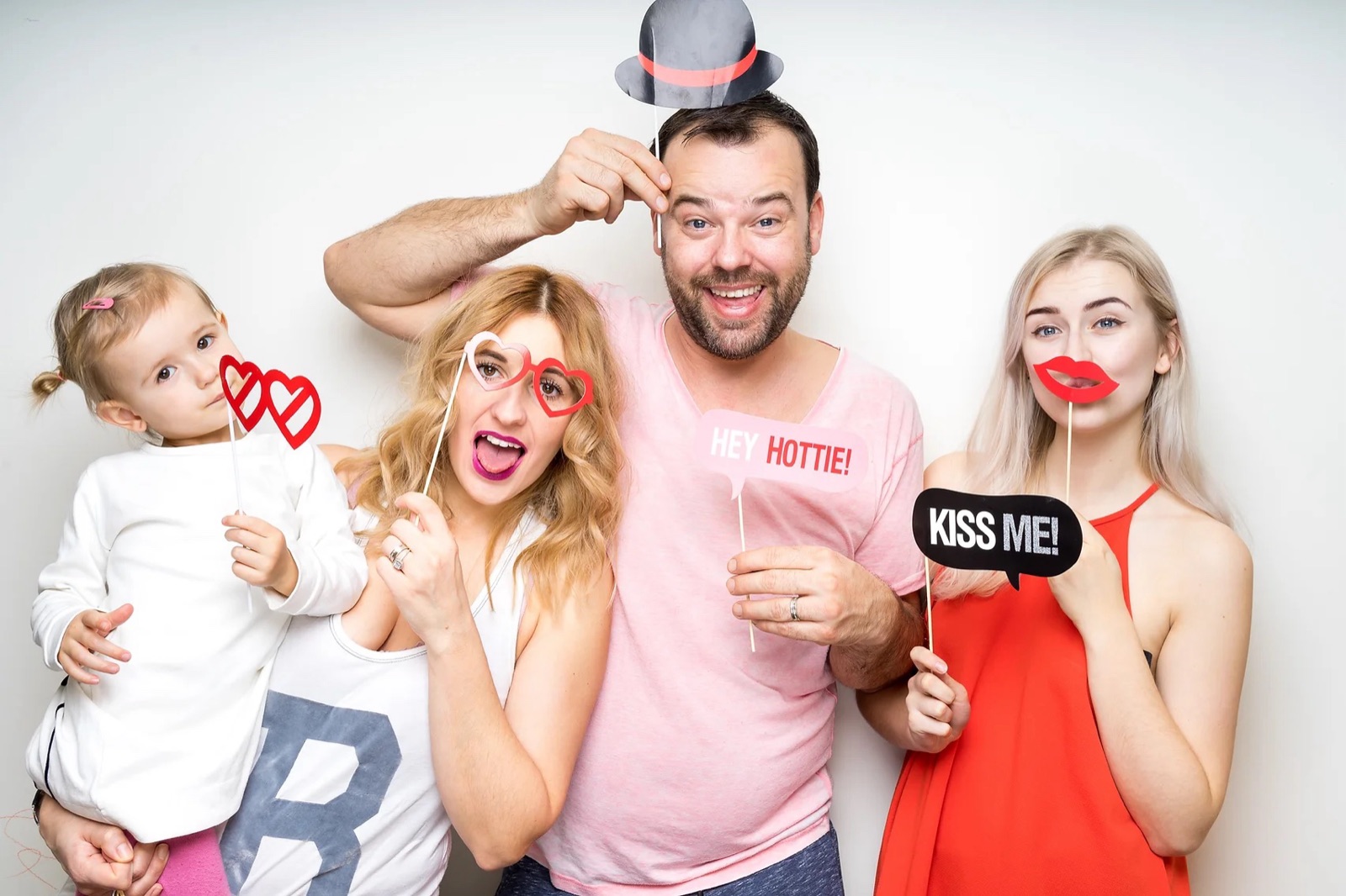 Familie zâmbitoare cu accesorii amuzante - pălărie, ochelari și pancarte