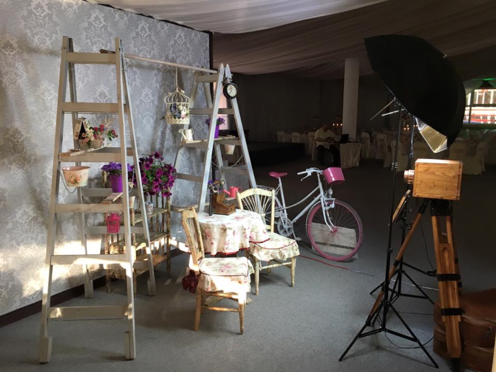 Colț vintage de eveniment cu scărițe decorative, bicicletă și cabina foto în fundal